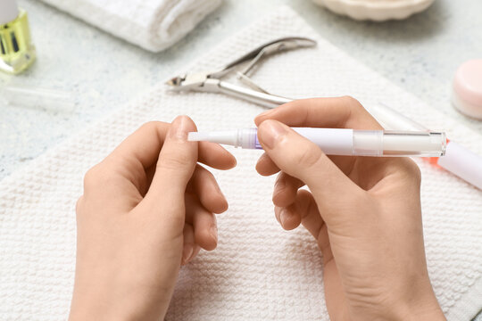 Female hands with cuticle oil pens, towel and cutter on blue grunge background, closeup