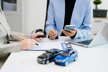 Car insurance consultation using smartphone and documents. Advisor and customer reviewing digital insurance service, auto policy, finance, technology