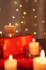 warm candlelit scene with glowing bokeh, featuring red wrapped gift boxes and luminous candles,...