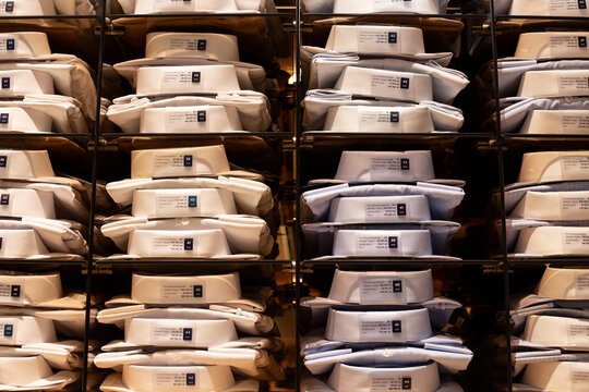 Shelf with folded shirts of various sizes. Symmetrical photo of premium shirts for business person. Buying new shirt at clothing store. Choosing quality clothing for classic outfit