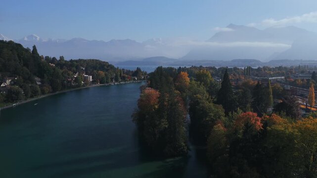 Thunersee Lake Thun Flusswelle Aare River aerial drone Thun Switzerland Schweiz Swiss Alps Fall Autumn sunny morning clouds haze Bernese Oberland Interlaken still water boats ferry upwards motion