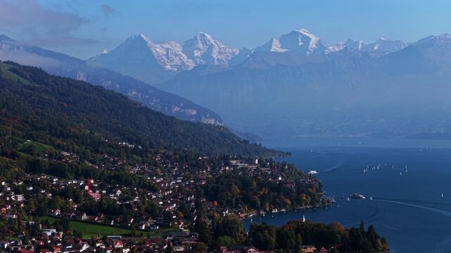 Swiss Alps Grindelwald Jungfrau mountains Bernese Oberland Thunersee Lake Thun aerial drone Thun Switzerland Schweiz Fall Autumn sunny morning low clouds haze Interlaken boats pan right