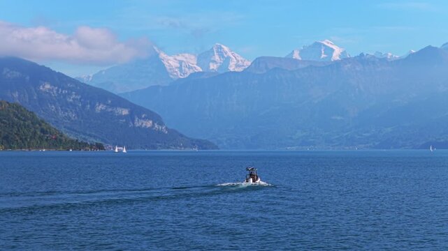 Powerboat Swiss Alps Grindelwald Jungfrau mountains Bernese Oberland Thunersee Lake Thun aerial drone Thun Switzerland Schweiz Fall Autumn sunny morning low clouds haze Interlaken circle right motion