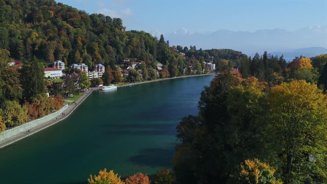 Thunersee Lake Thun Flusswelle Aare River aerial drone Thun Switzerland Schweiz Swiss Alps Fall Autumn sunny morning clouds haze Bernese Oberland Interlaken still water boats walk path forward pan up