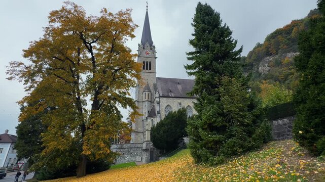 Fall Autumn morning Cathedral Chapel Katherdrale St Florin Neo gothic building parish church Vaduz Liechtenstein Lichtenstein windy falling golden yellow leaves cloudy grey skies October November