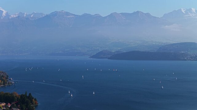 Sailboats Swiss Alps Grindelwald Jungfrau mountains Bernese Oberland Thunersee Lake Thun Flusswelle Aare River aerial drone Thun Switzerland Schweiz Fall Autumn sunny morning clouds Interlaken pan