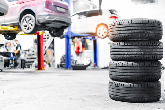 Stack of tires in a busy auto repair shop with cars on lifts in the background