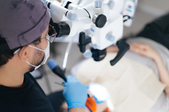 Male surgeon performing microsurgery in medical clinic with microscope