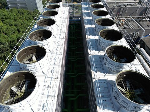 Top down aerial view of green AI data center cooling towers next to forest.