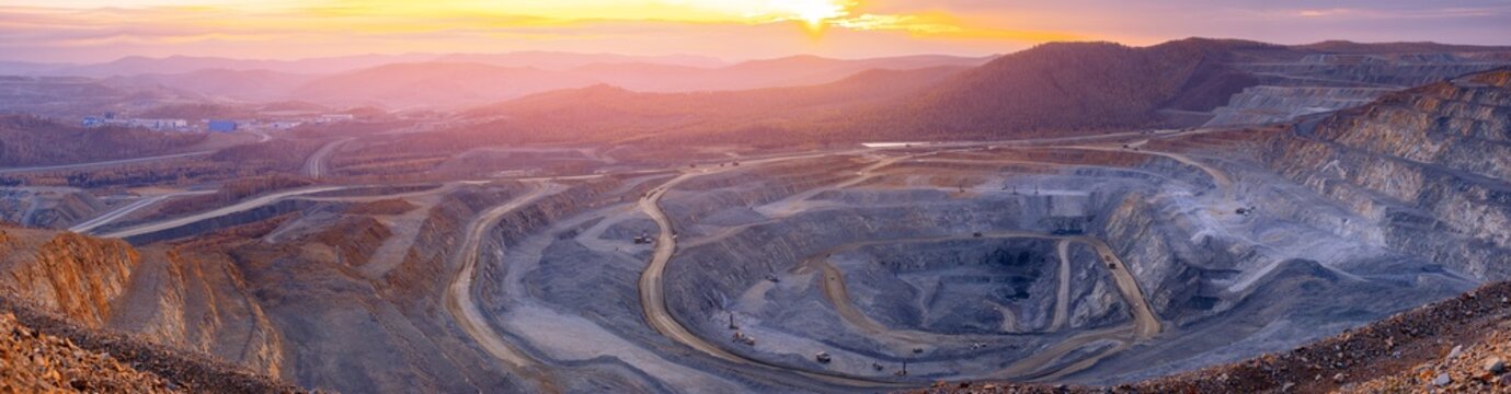Aerial Panorama of industry Open Pit Mine at Sunset with heavy trucks and machine