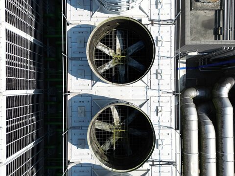 Top down close up aerial view of large industrial cooling tower fans and ventilation grilles.