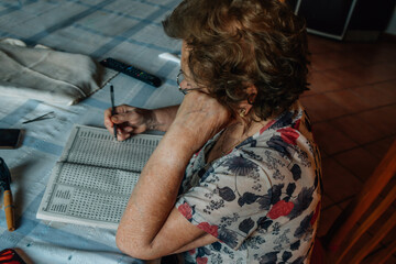 senior woman at home writing puzzles or crosswords