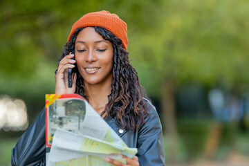 young woman traveling talking on phone outdoors looking at map