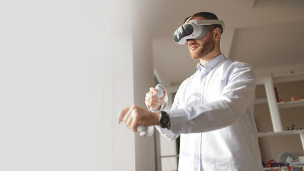 Young caucasian male engineer engages in virtual reality gaming with vr headset and controllers
