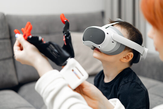 Young caucasian boy experiencing virtual reality with vr headset and toy robotic arm made by 3D printer - Powered by Adobe