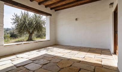 Rustic Mediterranean-style patio with stone tile floor, white stucco walls, wooden ceiling beams, and outdoor olive tree view