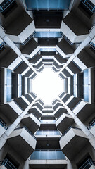 Symmetrical view looking up at modern geometric apartment balconies with dramatic perspective and open sky