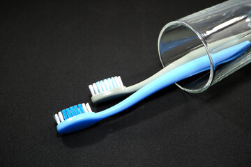 A set of colorful toothbrushes in a clear glass on black background closeup shot, conveying a sense of oral hygiene and daily routine with a touch of vibrancy.