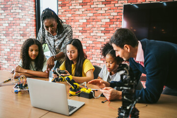 Three diverse students and two inclusive teachers collaborate on a robotics activity using electronics and a laptop, promoting STEM education, teamwork, and hands-on learning in a dynamic classroom.