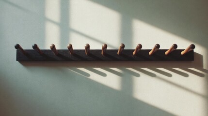 Fototapeta premium Wooden coat rack hanging on a white wall. the coat rack is made of dark wood and has multiple rows of wooden pegs arranged in a horizontal line.