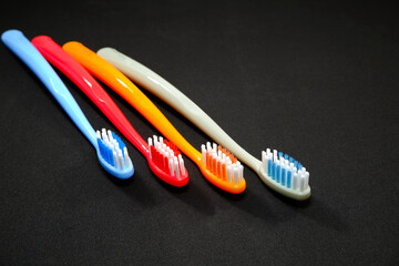 Group of vibrant color toothbrushes layered on a black background, conveying a sense of cleanliness and oral hygiene and daily routine with a touch of vibrancy.