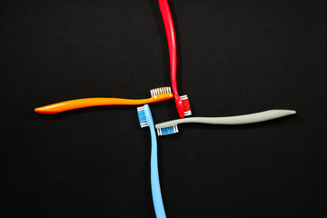 Colorful toothbrushes in red, orange, blue, and grey arranged on black background closeup view, Daily routine concept photography