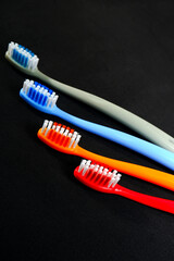 Colorful toothbrushes layered on black background closeup view, Morning routine concept photography selective focused.
