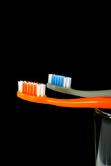 A set of colorful toothbrushes on clear glass on black background closeup shot, conveying a sense of oral hygiene and daily routine with a touch of vibrancy. Selective focused 
