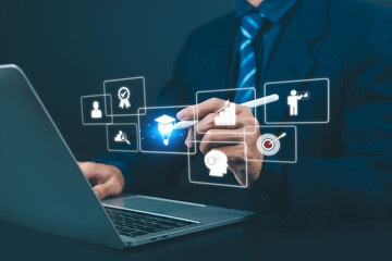 E-learning and knowledge management concept with businessman using laptop and digital interface icons, representing online education, skill development, training and performance growth.