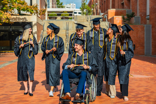 Diverse students celebrating graduation, a man in wheelchair holding diploma