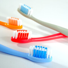 Vibrant toothbrushes in red, orange, blue, and grey arranged on white background, evoking a sense of cleanliness and oral health, Daily routine concept photography