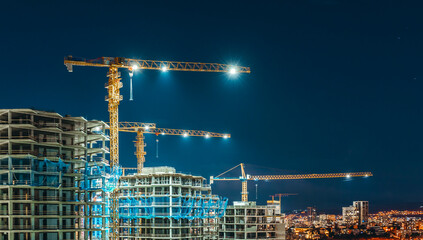 Construction Site at Night with Illuminated Tower Cranes and Building Skeletons