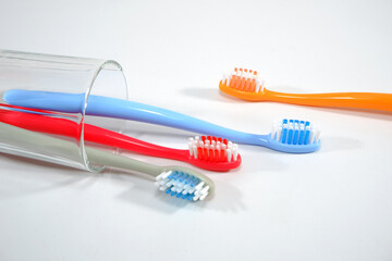 Vibrant toothbrushes in red, orange, blue, and grey arranged on white background, evoking a sense of cleanliness and oral health, Daily routine concept photography