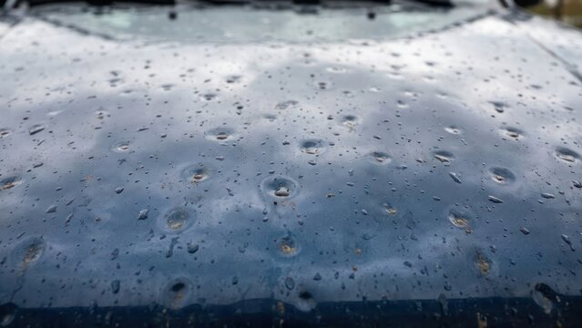 Hail damage on car hood closeup showing many small metal dents