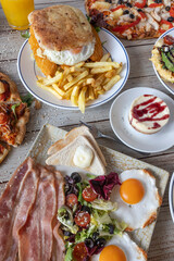 Brunch table with various foods including bacon and eggs