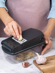 A woman grates garlic with a vegetable peeler, Authentic photograph, not AI-generated