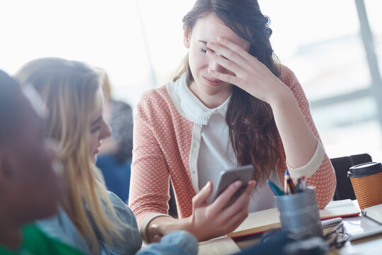 Sad, woman and students with phone in class for bad news, test results and failed course. Stress, person and friends with mobile for scholarship rejection, emotional reaction and message notification
