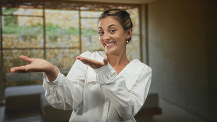 Fototapeta premium Woman showing open palms and smiling in studio, white blouse with visible hands and expressive face; friendly surprise.