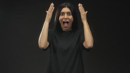 Woman with hands covering eyes, then revealing with hands raised, tongue out, clapping and smiling in a black studio sequence; playful joy gratitude.