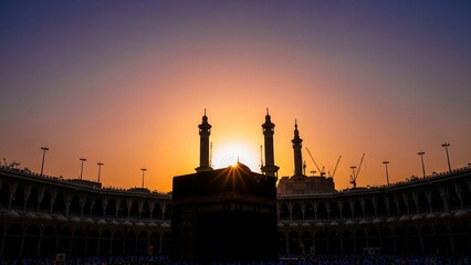 Holy Kaaba in Masjid Al-Haram, Mecca, Saudi Arabia during sunset with silhouette of minarets