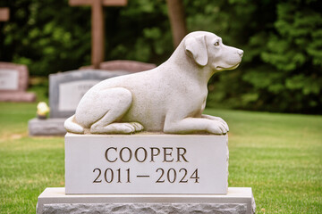 Gravestone with dog stone sculpture in a cemetery. Memorial for a beloved pet and pet loss remembrance