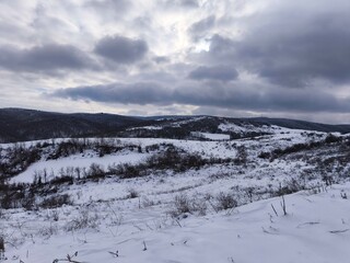 Snowy Hills and Frozen Valley Under Dramatic Winter Sky