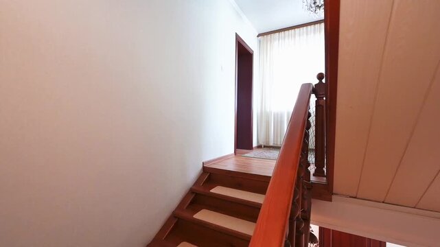 hallway with a dark wooden door, a wooden staircase with turned balusters and a handrail, light-colored walls, and an open doorway in the background.