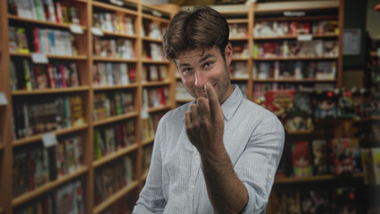 Man beckons with both bare hands between tall bookshelves in a library building, smiling and leaning forward; invitation playful.