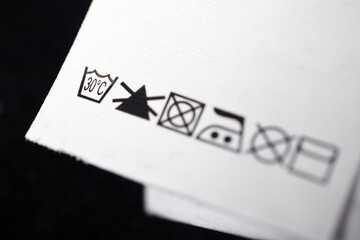 Care label with washing instructions on a dark fabric garment