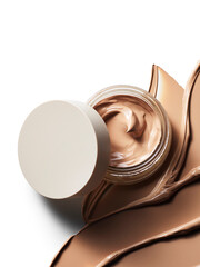 Luxurious cream foundation makeup product shown open next to rich, blended cosmetic swatches