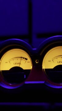 Close-up of two analog VU meters measuring audio signals on professional equipment. Concept of music production, sound engineering, volume control, and professional recording.