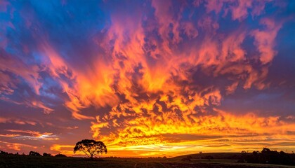 Fiery Sunset Spectacle - Dramatic Clouds Painting the Sky with Vibrant Hues Over Silhouette Landscape.