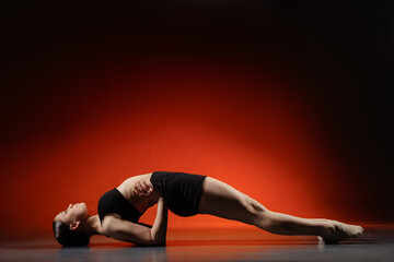 Athletic woman doing bridge backbend stretch in studio with red copy space