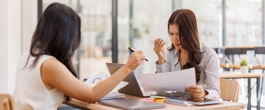 Business team women getting stressed and covering face with hands while colleague comforting her at office desk
